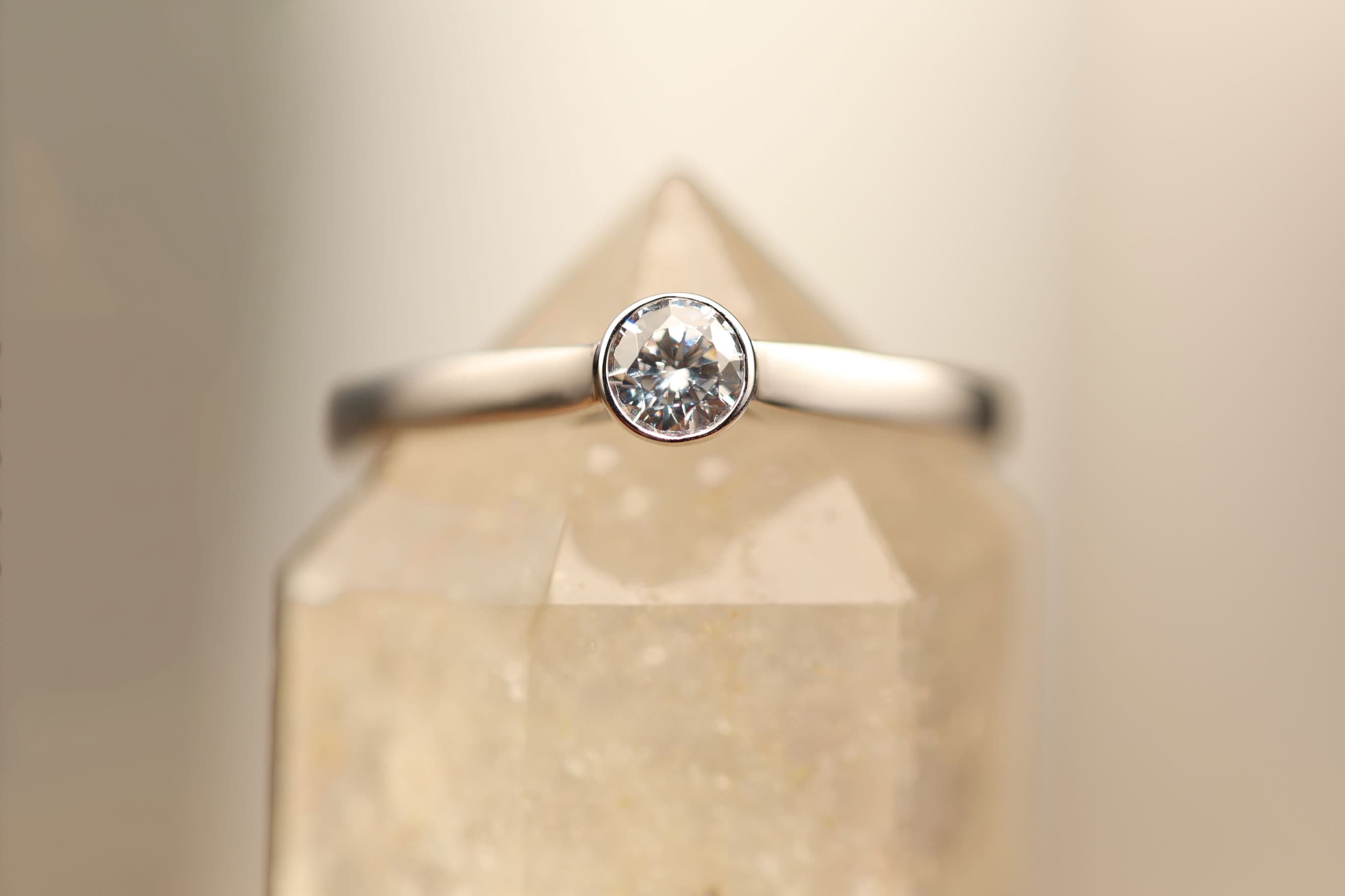 Silberner Solitär-Ring mit rundem Brillant in Zargenfassung auf einem Bergkristall