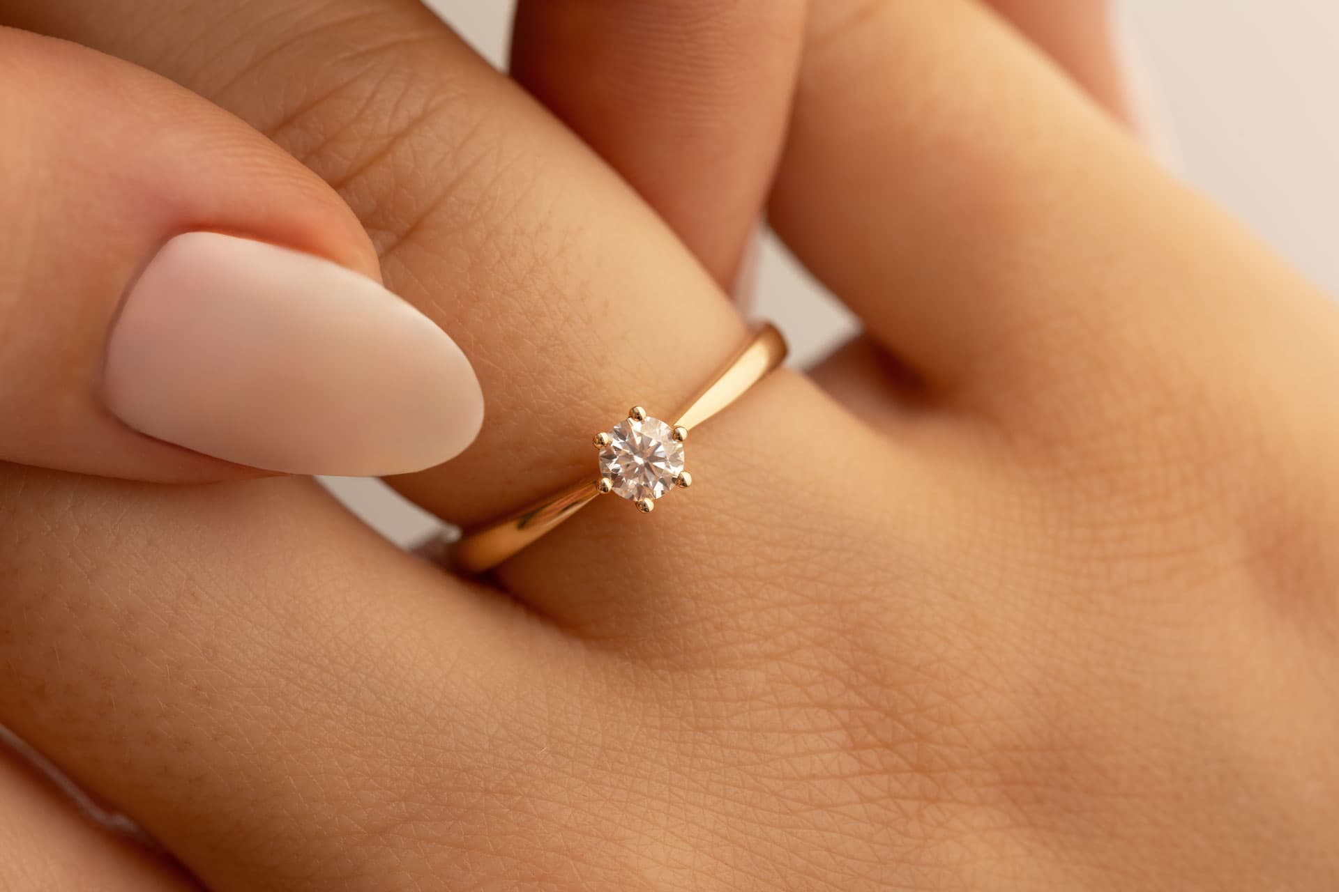 Handgefertigter Verlobungsring aus Gold mit einem Diamanten aus Haaren auf hellem Holz